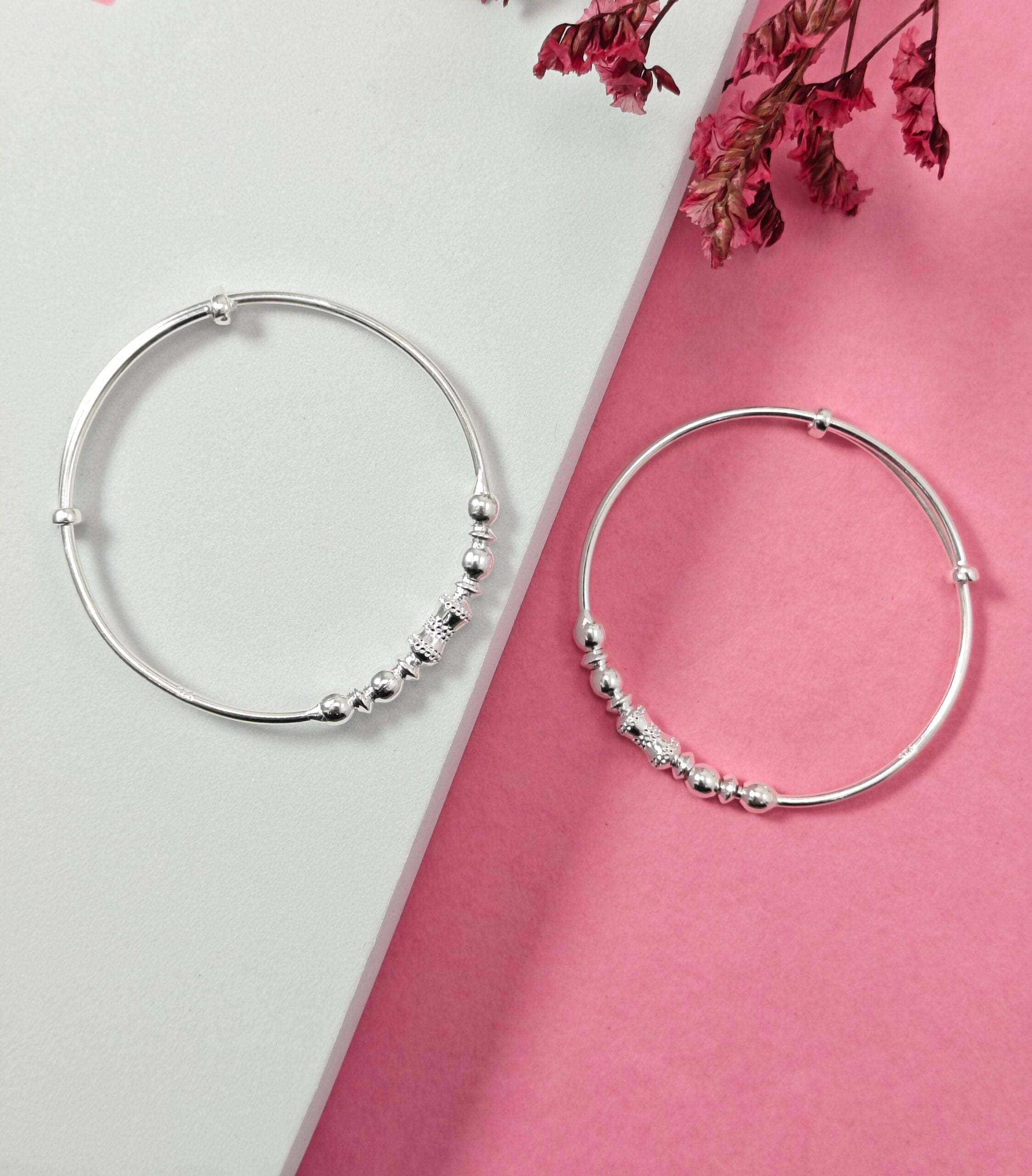Silver hoop earrings with bead detailing on a pink and white background